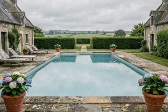Piscine extérieure avec architecture en pierre bretonne traditionnelle et jardin verdoyant en Bretagne