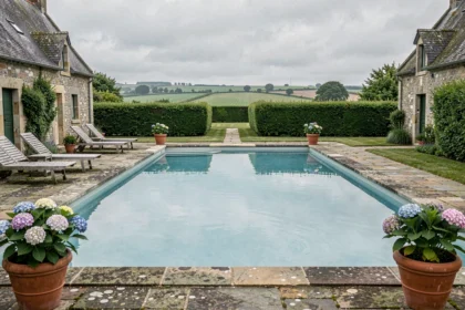 Piscine extérieure avec architecture en pierre bretonne traditionnelle et jardin verdoyant en Bretagne